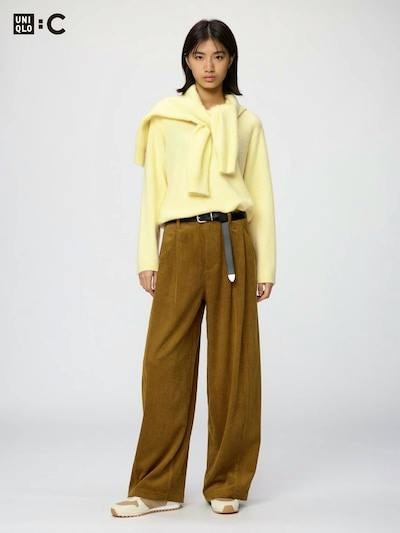 Full-length photo of a model wearing brown corduroy volume pants (mens pants, polyester) with a yellow sweater.