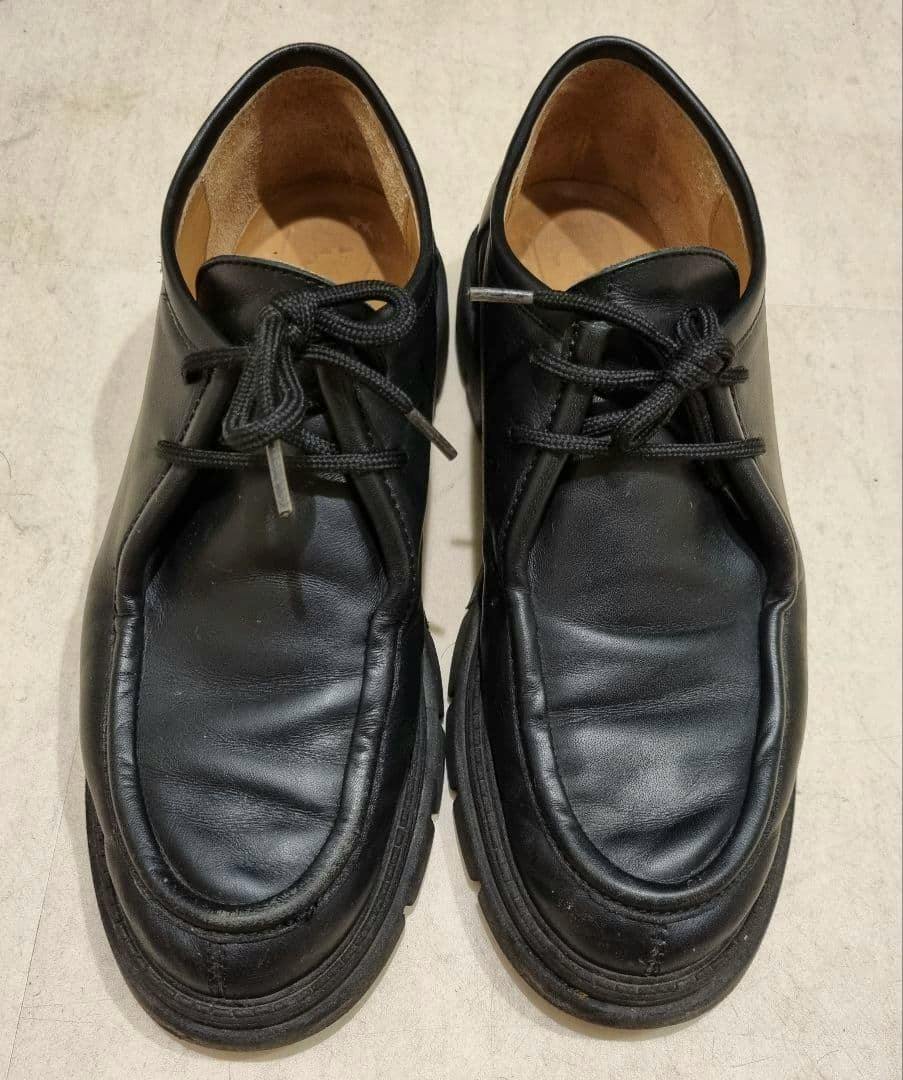 Top-down photo of a pair of black leather CORSO ROMA 9 Tyrolean shoes on a light surface.