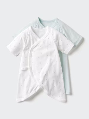 Two baby kimono-style undershirts overlapped, one white with a small dot print and one pale green, on a plain light background.