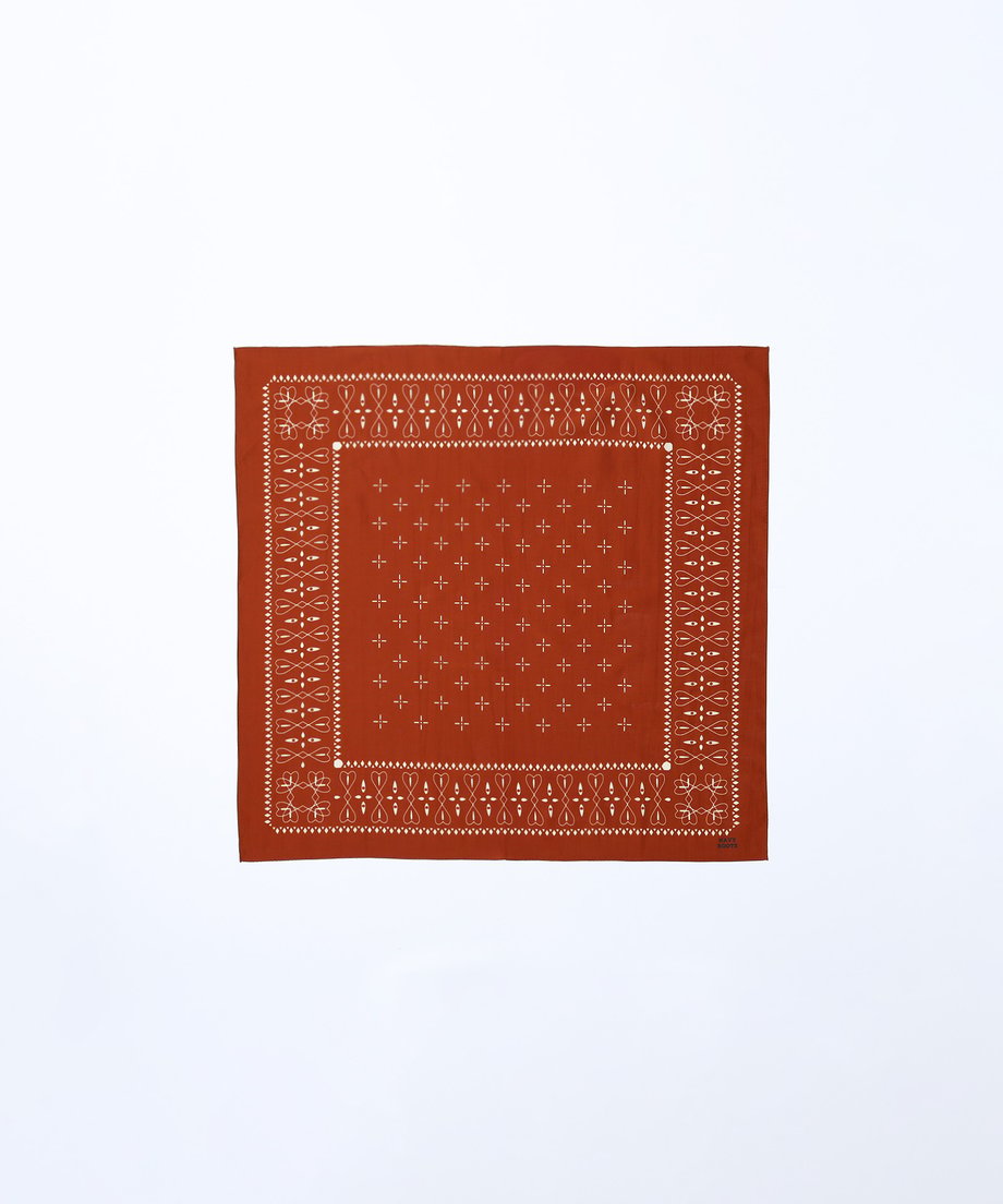 A rust-colored square cotton bandana with a white patterned bandana print on a white background.