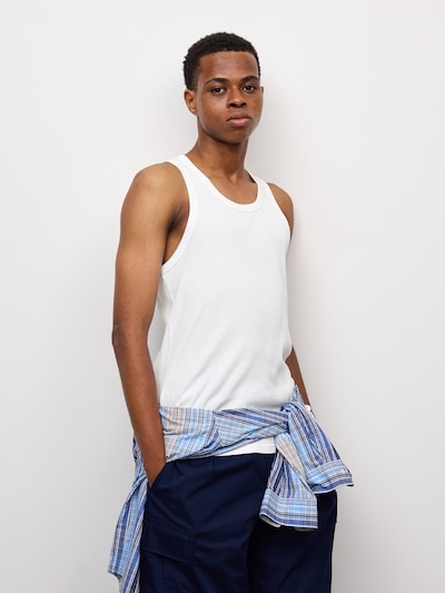 Male model wearing a white cotton rib tank top against a plain light background.