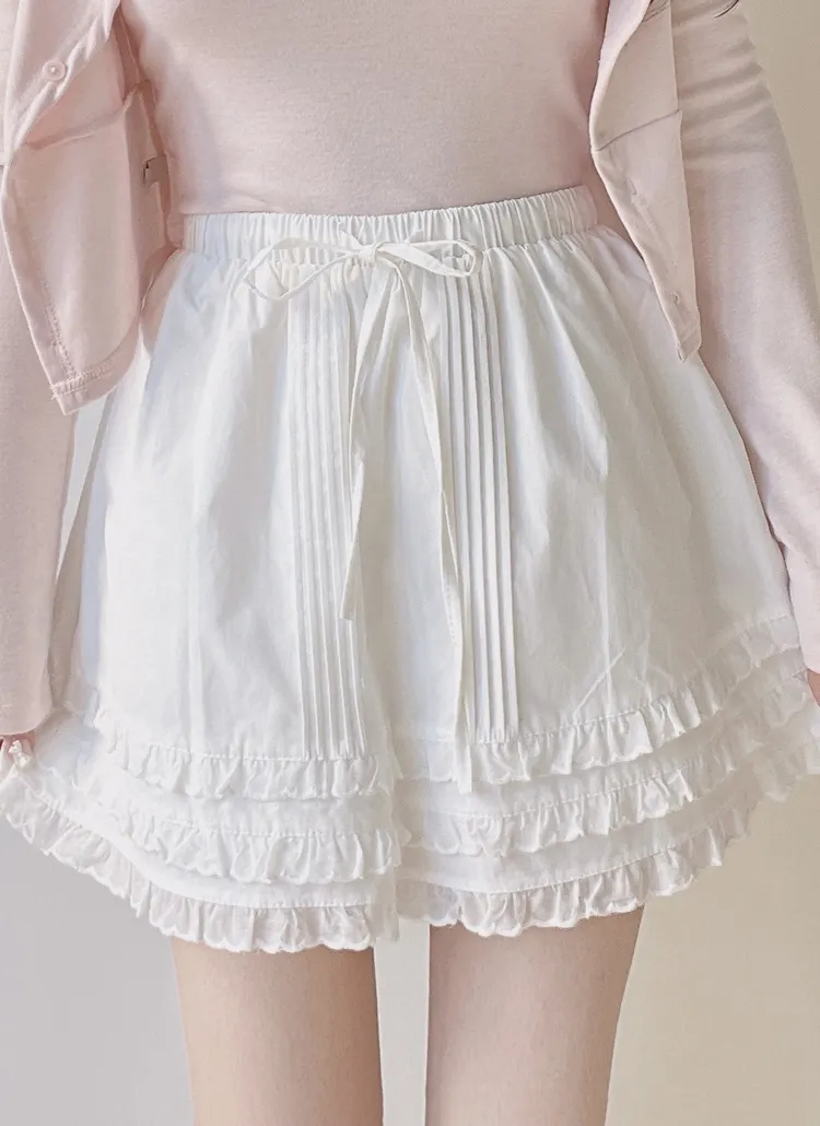 White cotton mini skirt with elastic drawstring waist and layered frill hem worn by a model.