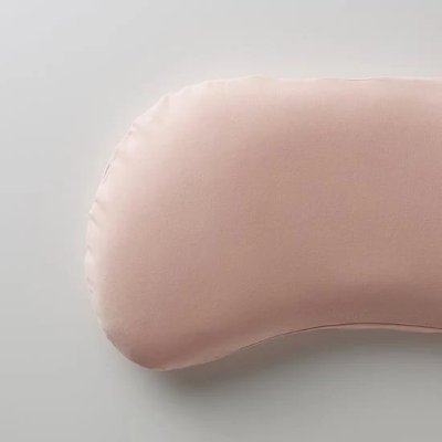 Close-up photograph of a pink cotton pillow cover fitted over a curved pillow.