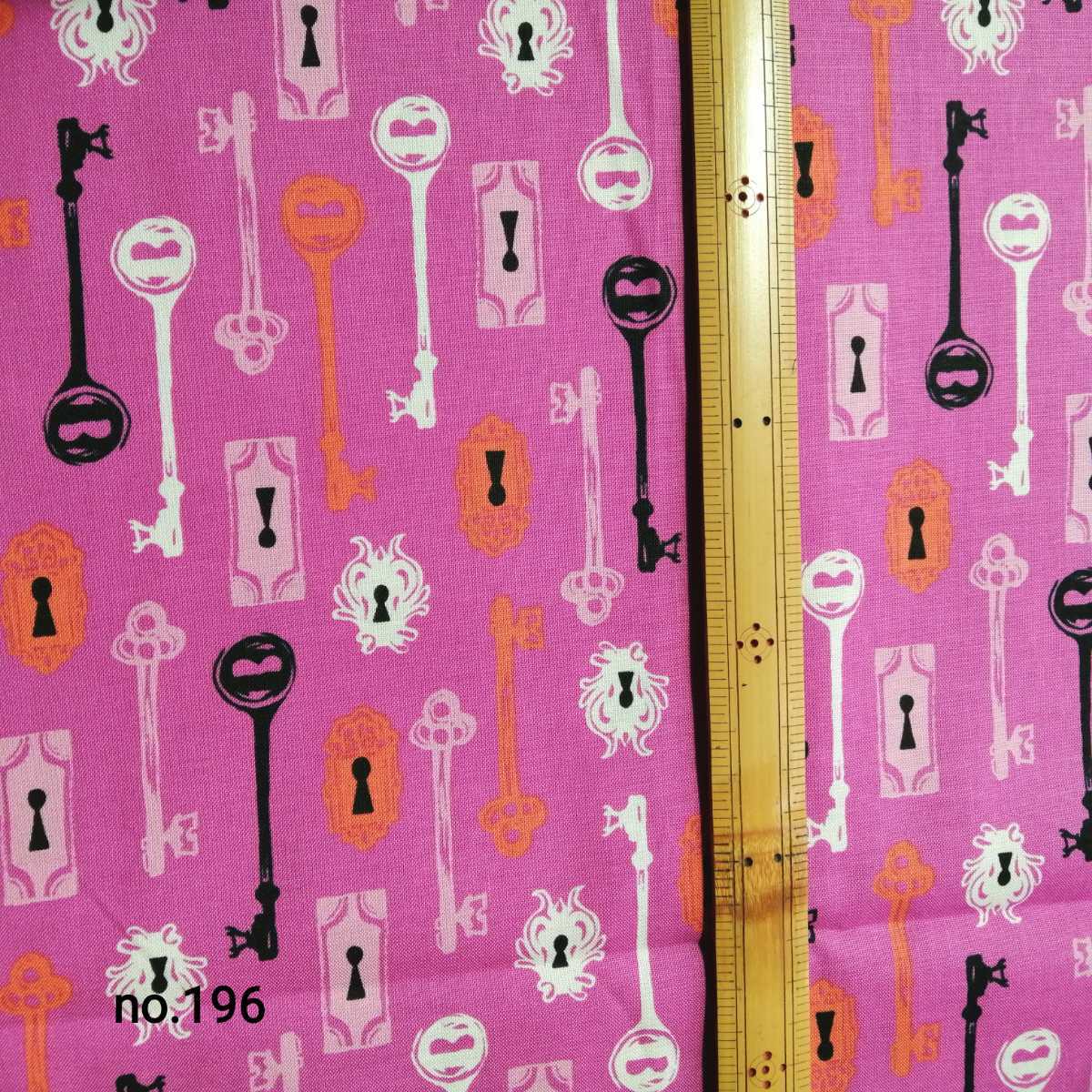 Pink cotton fabric with key and keyhole Halloween motifs laid flat with a ruler for scale.