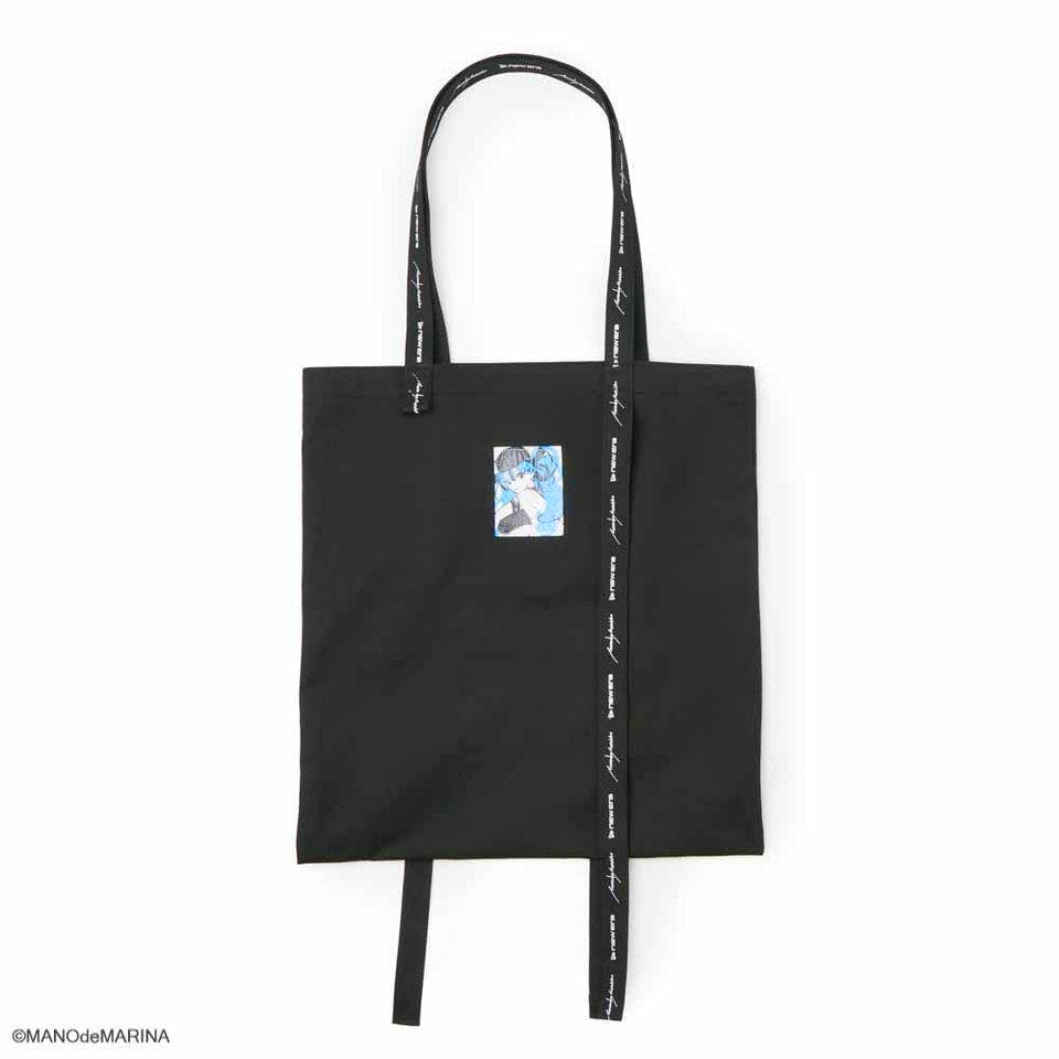 Front view of a black cotton twill tote bag with long printed handles and a small illustrated patch on the front.