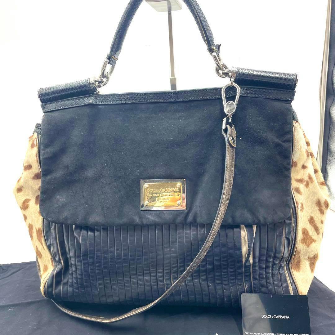 Front view of the bag (cow leather) with top handle and long strap, black front panel and leopard-patterned side panels displayed on a stand.