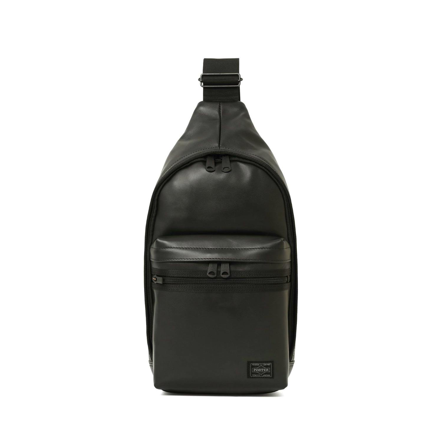 Front view of a black cow leather sling shoulder bag with a front zip pocket and adjustable strap on a white background.