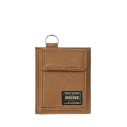 Brown cow-leather wallet shown from the front with a flap pocket and a small rectangular PORTER Tokyo-Japan logo patch.
