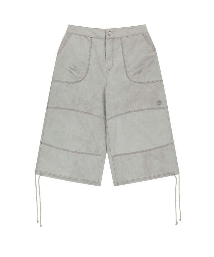 Flat lay of ice beige zigzag pants showing front pockets, curved seam details, and drawstring hems.