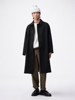 Male model wearing the Cozy Melton Balmacaan coat in black standing against a white background.