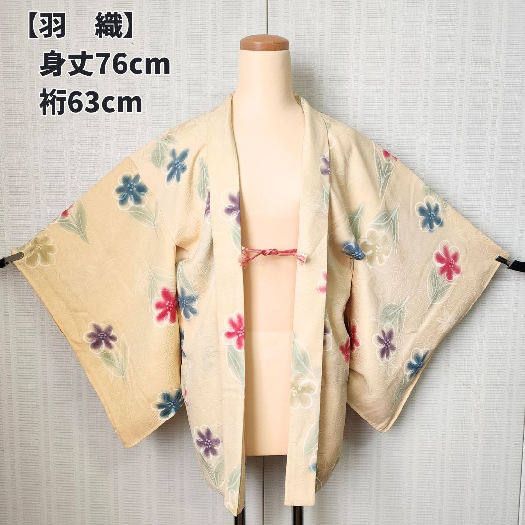 Cream-colored haori kimono coat with colorful floral pattern displayed on a mannequin.