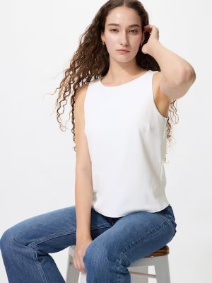 A seated woman wearing the white boat-neck bra top from the product.