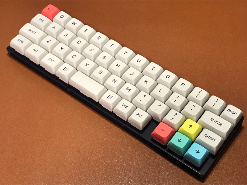 Compact CROSSARROW50 PC keyboard with white keycaps and colorful modifier keys on a brown surface.