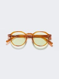 Front view of amber crown-panto sunglasses with light-tinted lenses on a pale background.