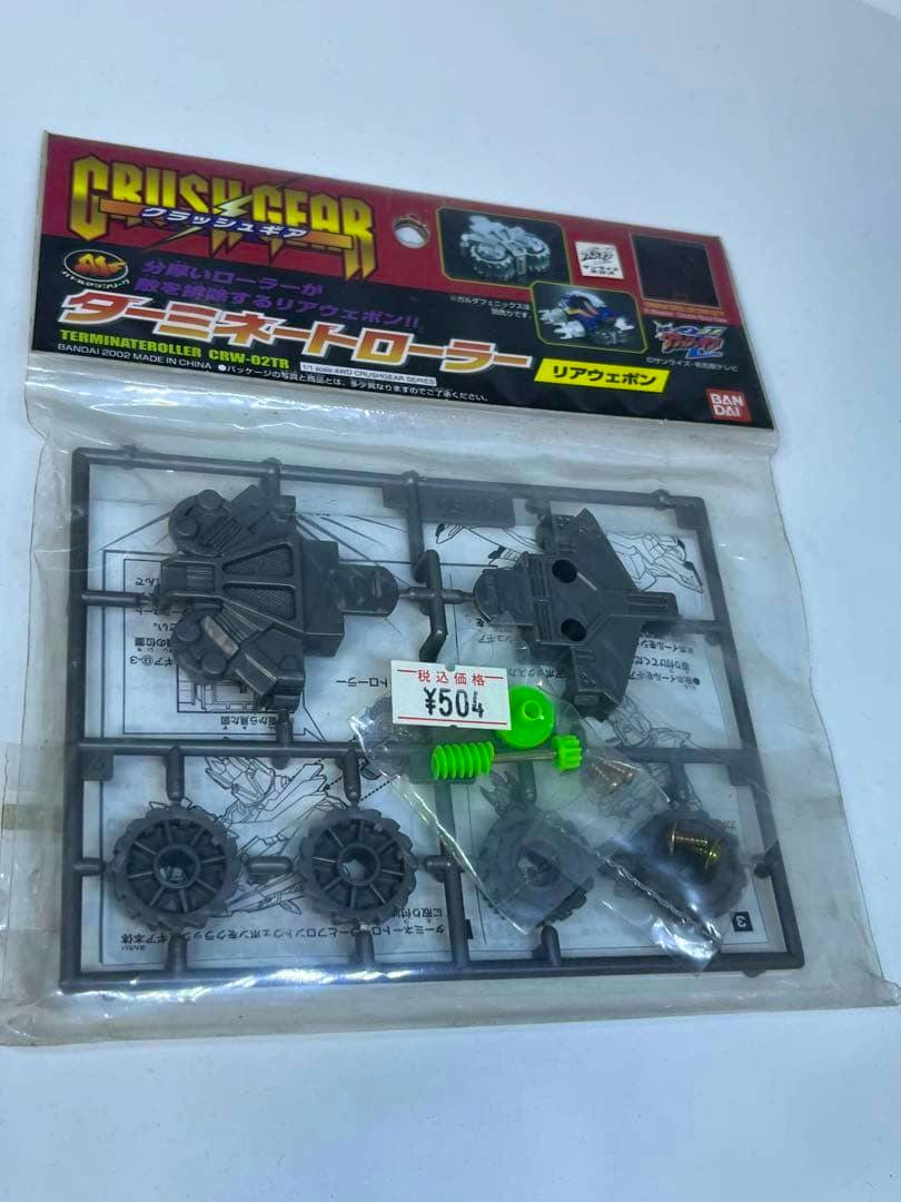 Front photo of the sealed packaged クラッシュギア custom parts (Terminate Roller rear weapon) showing the plastic sprue, small green components, and a ¥504 price sticker.