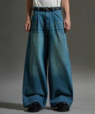 Front view of a model wearing wide baggy straight denim jeans with a belt and black shoes.