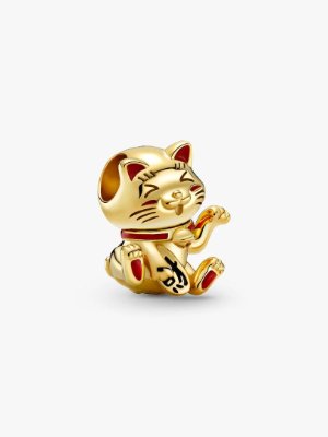 A gold fortune cat charm with red and black markings, sitting with a raised paw and a threading hole through the top.