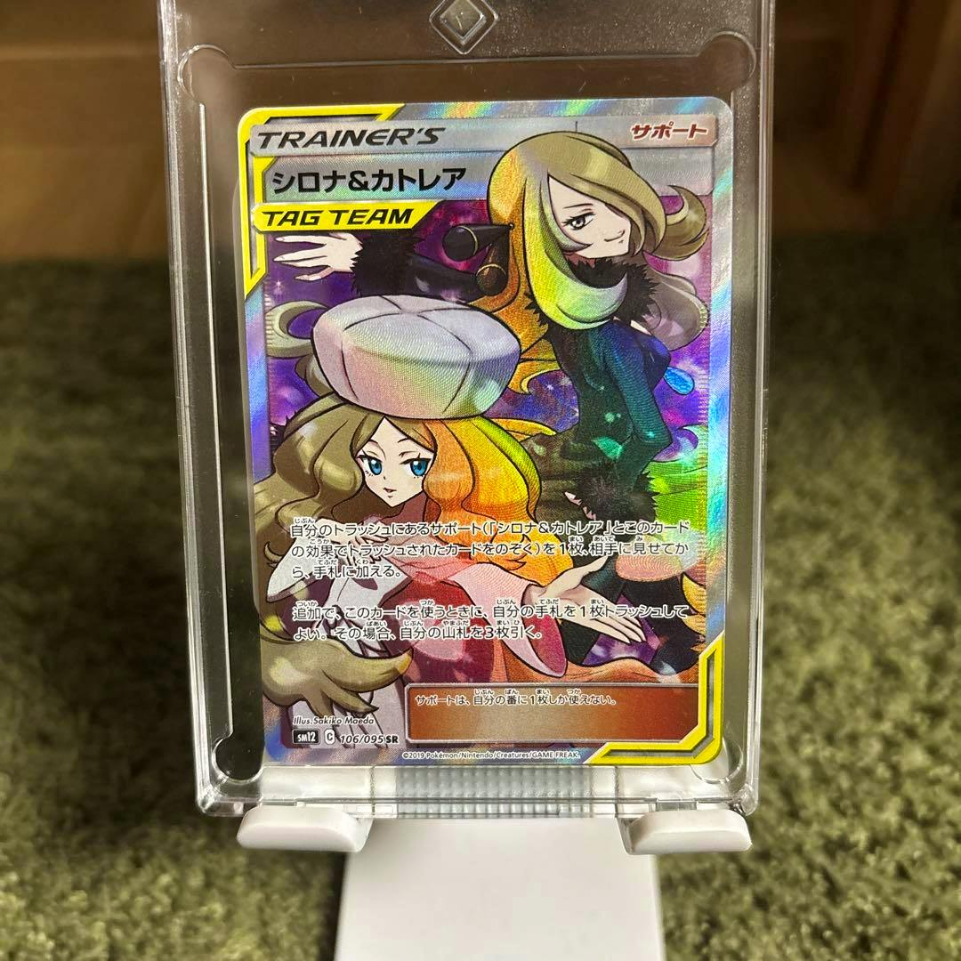 Front of the シロナ&カトレア SR Pokémon trading card in a clear plastic holder showing the holographic artwork and Japanese text.