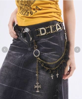 Model wearing the moon-buckle synthetic leather belt with a D.I.A. buckle and hanging decorative chains over a skirt.