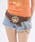 Close-up of a model's waist showing the star-buckle chain belt worn over shorts.