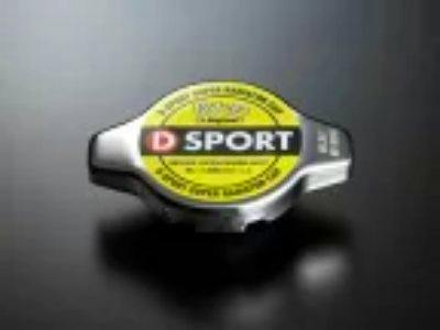 D-SPORT branded metal radiator cap with a yellow circular label and two side wings on a dark background.