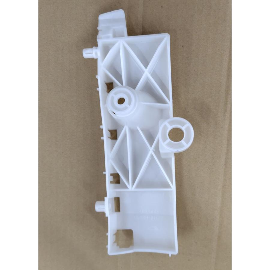 Left-side front bumper support (Daihatsu part 52116-B2040) laid on cardboard showing one side and mounting points.