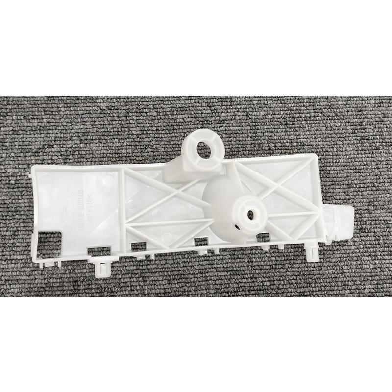 Right-side front bumper support for Daihatsu Mira Avy (part 52115-B2040) shown lying on a gray textured surface.