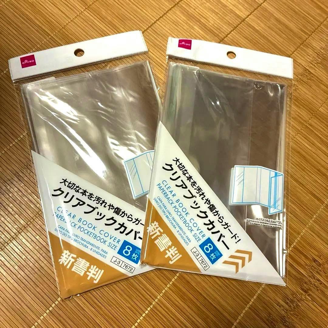 Two sealed packs of DAISO clear paperback book covers (8 sheets per pack) in their original packaging displayed on a woven surface.