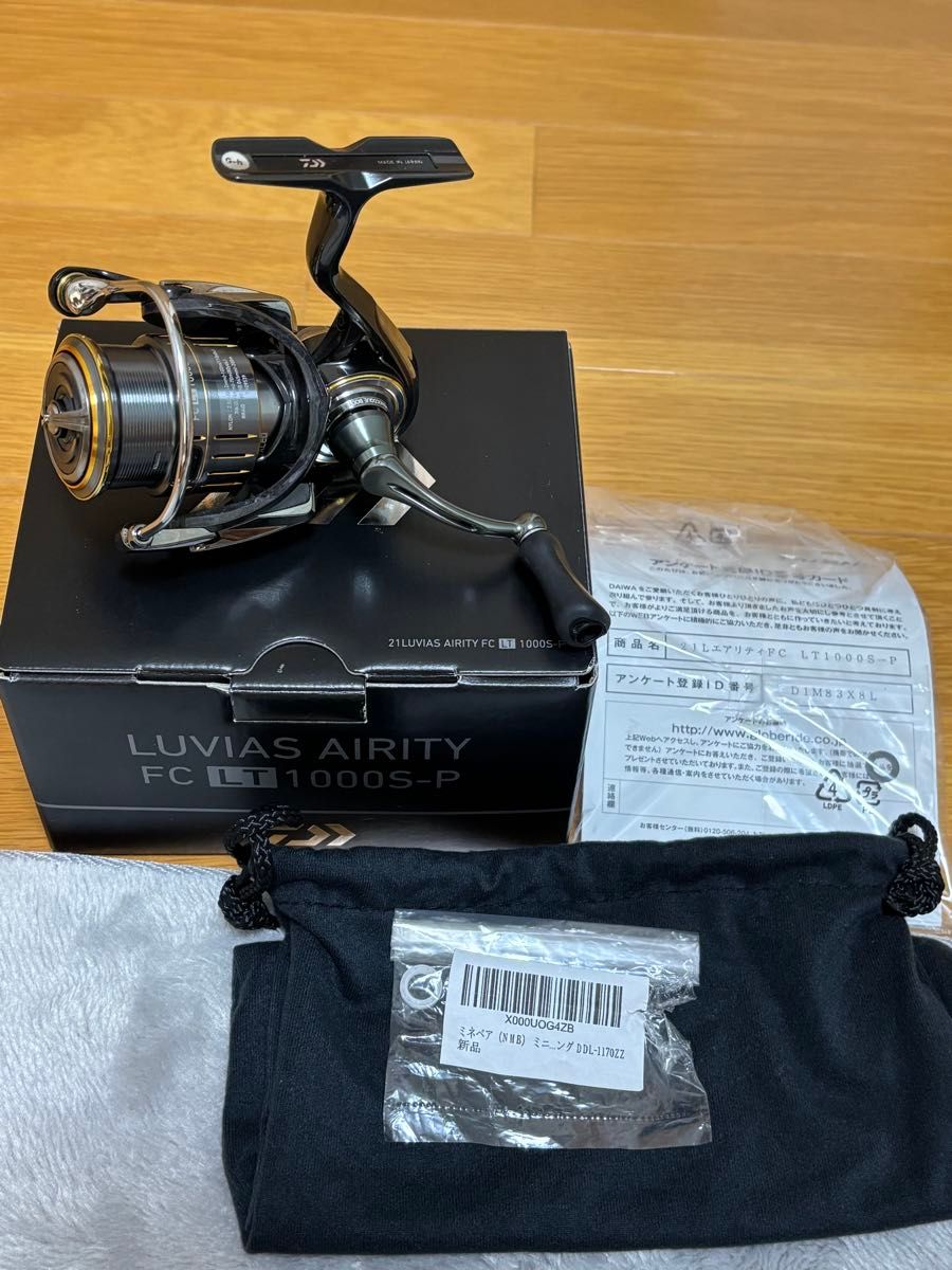 A 21ルビアスエアリティ FC LT 1000S-P fishing reel displayed on its box with a cloth pouch and paperwork visible.