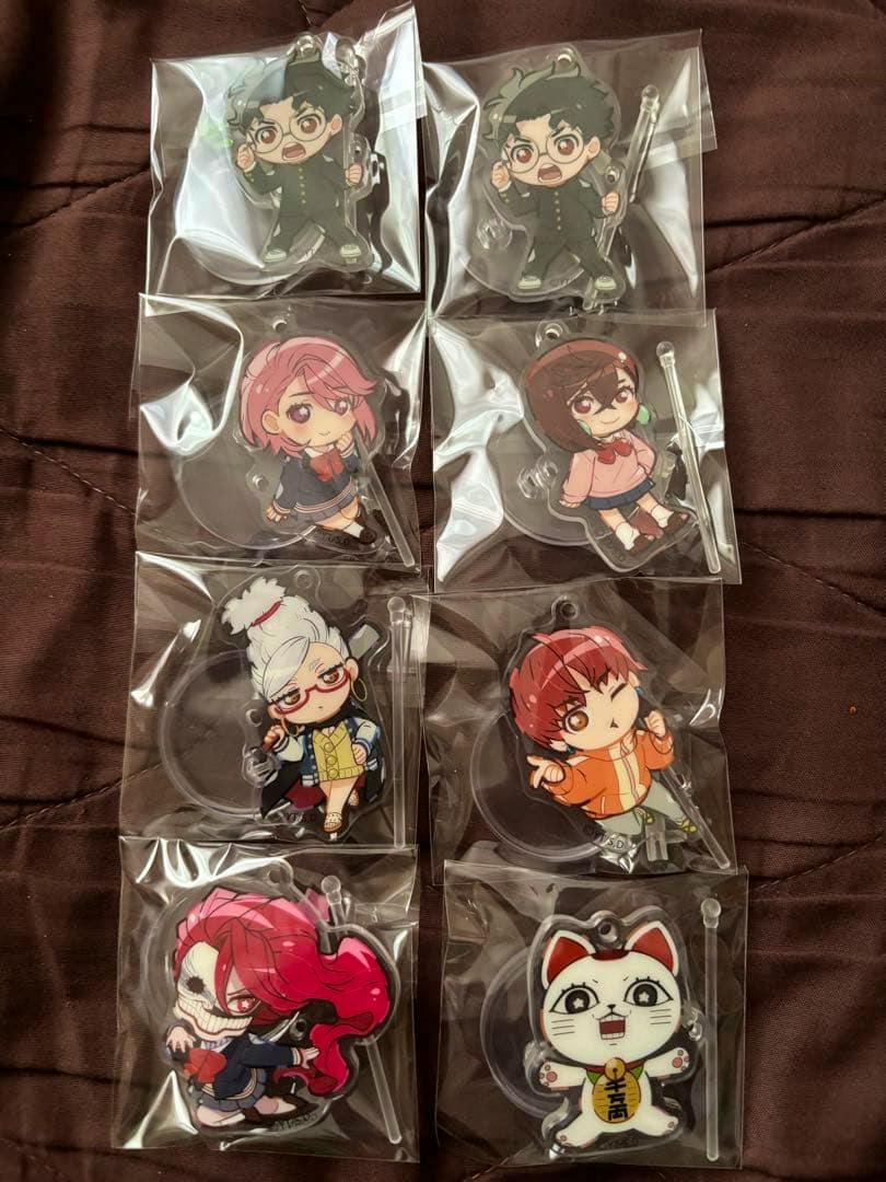 Eight packaged chibi acrylic decorative stand figures arranged in two columns on a dark surface.