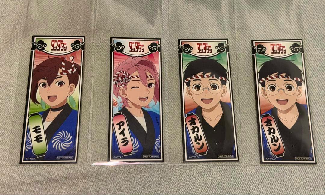Four rectangular stickers from the ダンダダン 怪ダン祭 set showing different anime characters laid side by side on fabric.