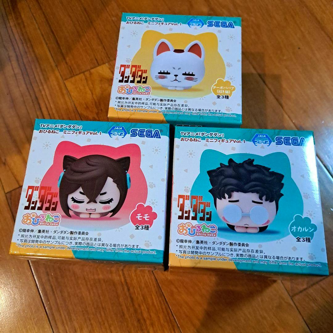 Three boxed Dandadan おひるねこ mini-figure boxes (3-piece set) arranged on a wooden floor.