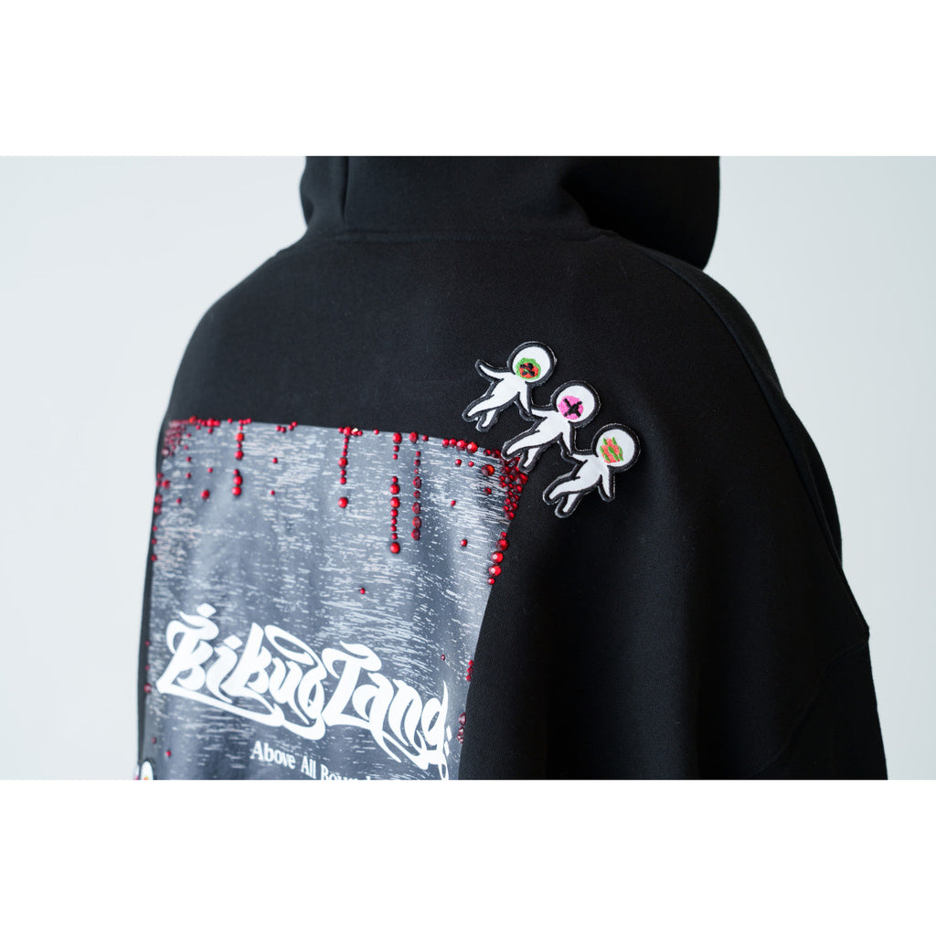 Three small embroidered patches are attached to the upper back of a black hoodie above a graphic panel.