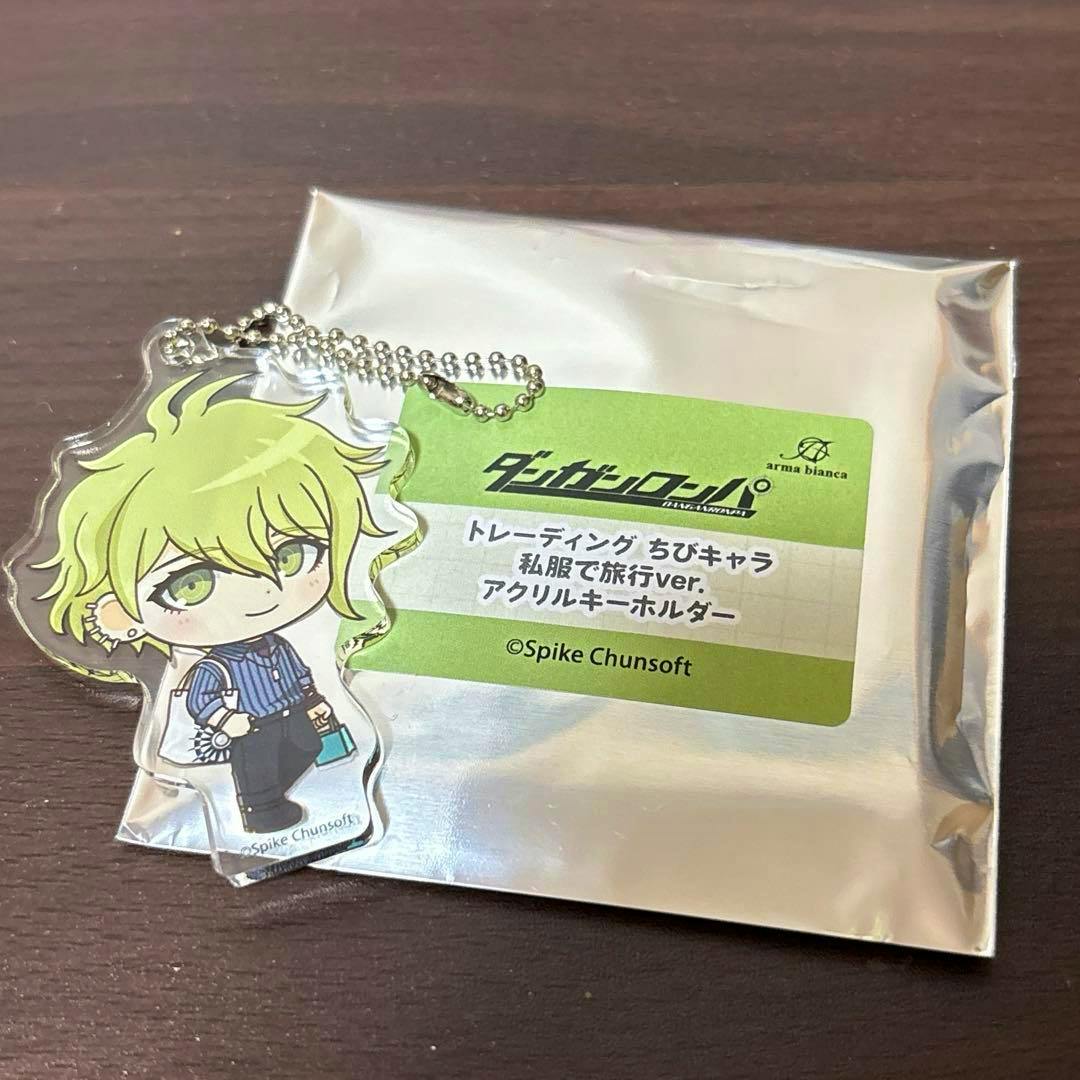 Chibi acrylic keychain of the character 天海蘭太郎 (Rantaro Amami) shown on a table next to its silver sealed packaging with a green product label.