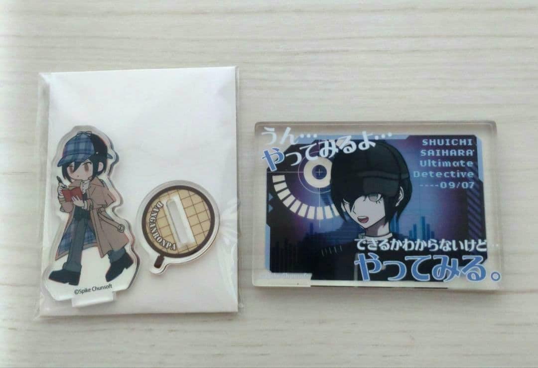 An acrylic block showing Shuichi Saihara artwork on the right with a small acrylic stand figure and round base on the left, photographed on a light wood surface.