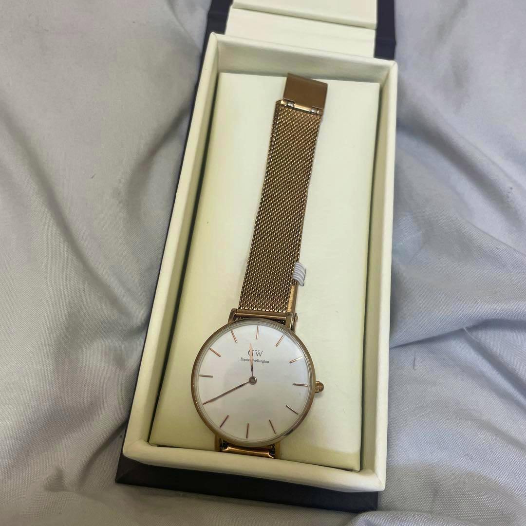 Daniel Wellington rose gold mesh watch shown in its box with the white dial visible.