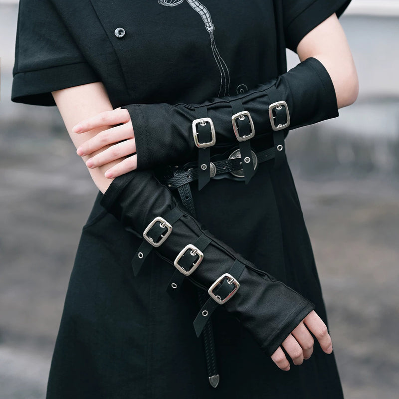 Black arm covers with multiple silver buckle straps worn on a model's forearms.