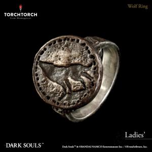 Close-up photo of the silver ring (Wolf Ring) showing a round medallion with a wolf design on a dark background.