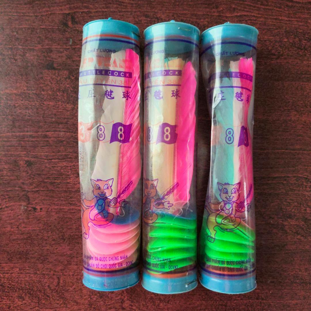 Three clear plastic tubes each containing a colorful feather shuttlecock are shown on a wooden surface.