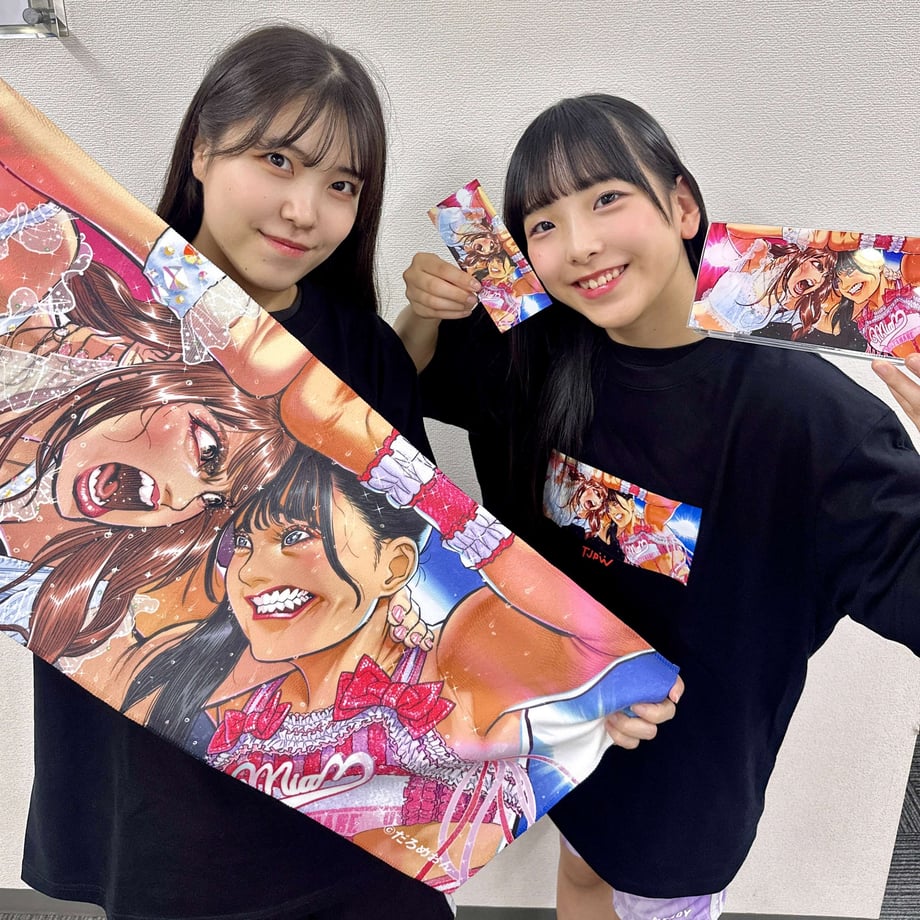 Two people holding the illustrated acrylic stand and other printed items featuring the product artwork.