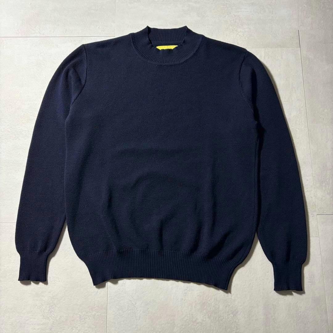A navy wool honeycomb knit sweater laid flat showing the crew neck, long sleeves, and ribbed hem and cuffs.