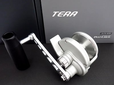 Silver DEEPLINER TERA fishing reel displayed on a dark surface next to its TERA product box.