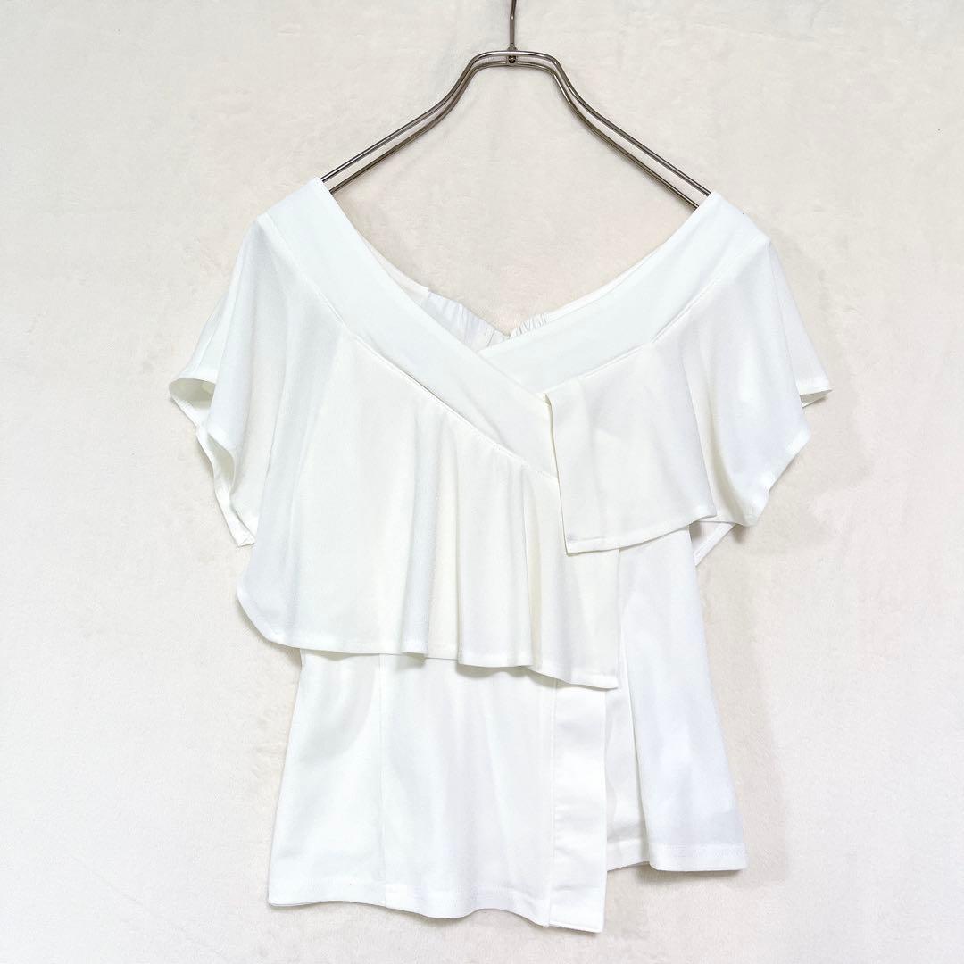 White sleeveless ruffled V-neck women's blouse hanging on a hanger.
