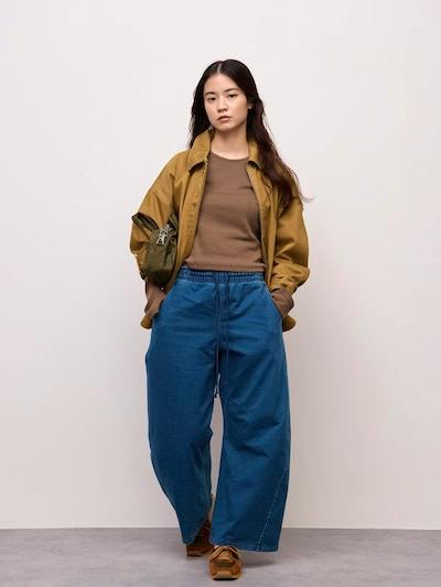 Woman wearing blue denim 3D barrel pants with an elastic waistband and wide legs.