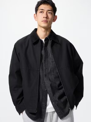 Male model wearing the men's zip-up short blouson jacket in black over a denim shirt and white T-shirt.