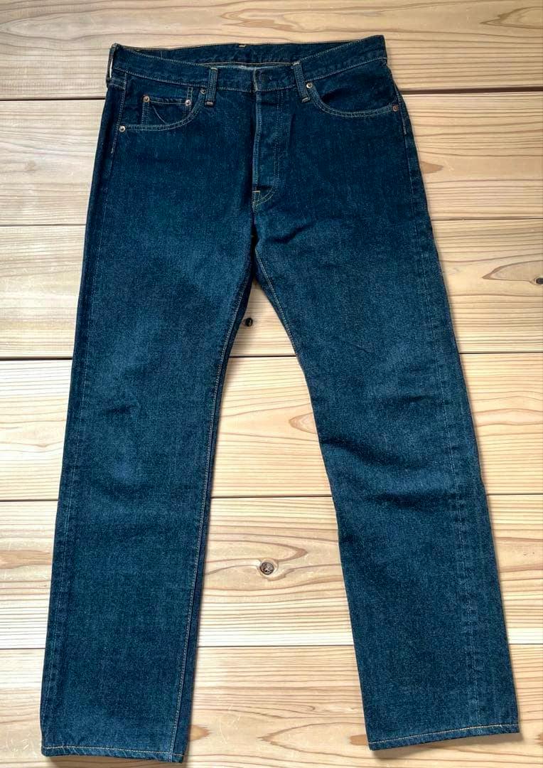 A pair of black denim jeans laid flat showing the front view with pockets and legs visible.