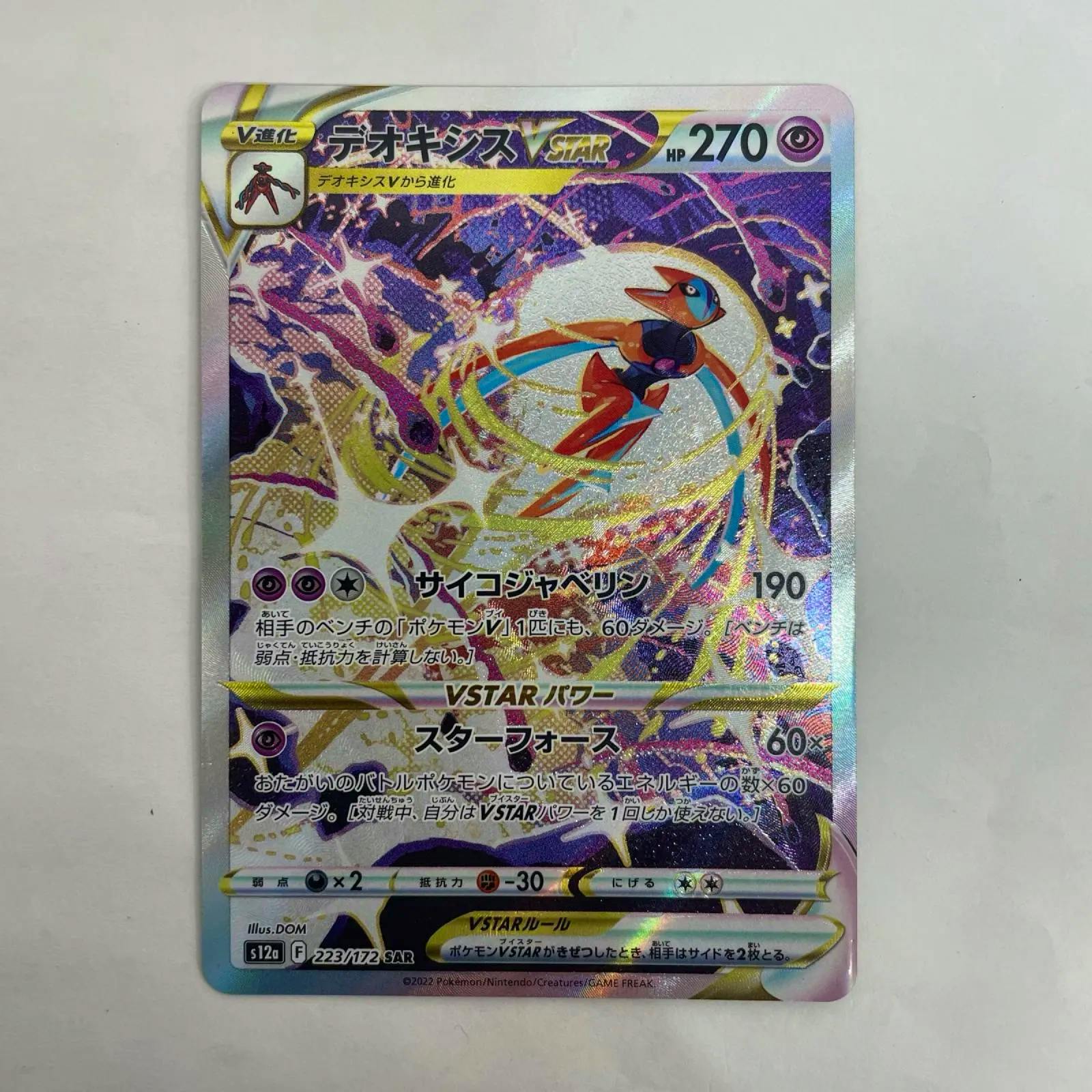 Photograph of the Deoxys VSTAR trading card (S12a-223) showing the holographic artwork and Japanese card text.