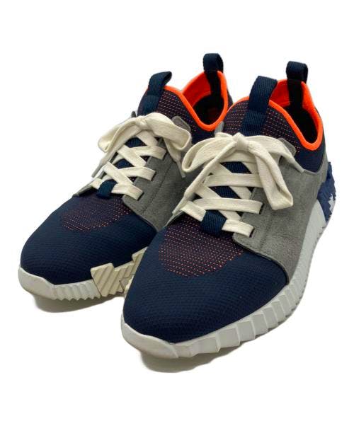 Pair of Depart sneakers in navy, gray, and orange textile with white laces shown from a front three-quarter view.