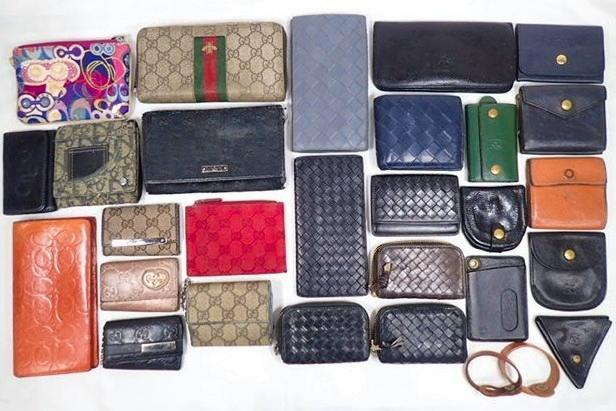 Array of assorted wallets, coin cases, and key cases from various brands laid flat on a white background.