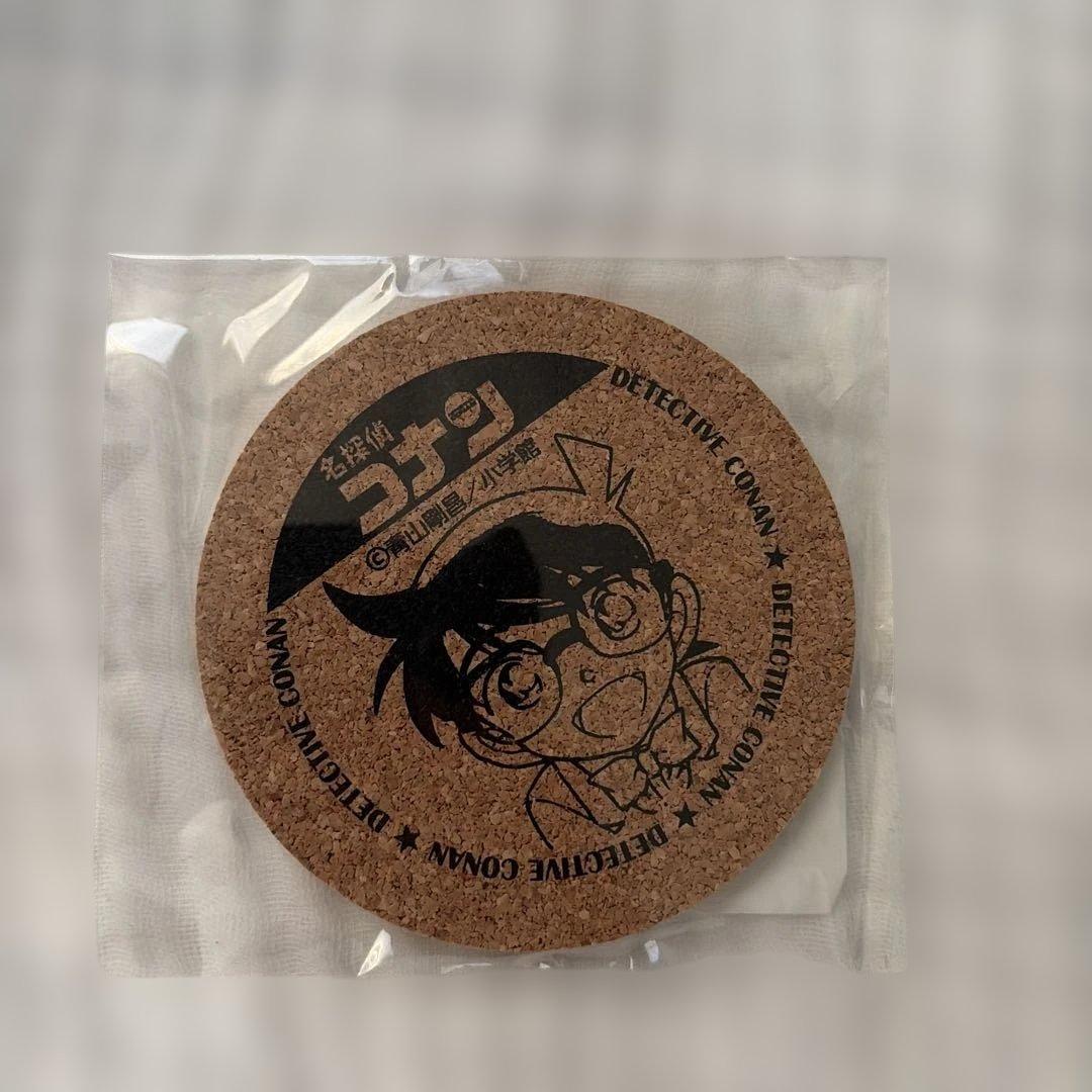Round cork coaster (about 10 cm) with a printed Detective Conan character and Japanese text, shown inside clear plastic packaging.